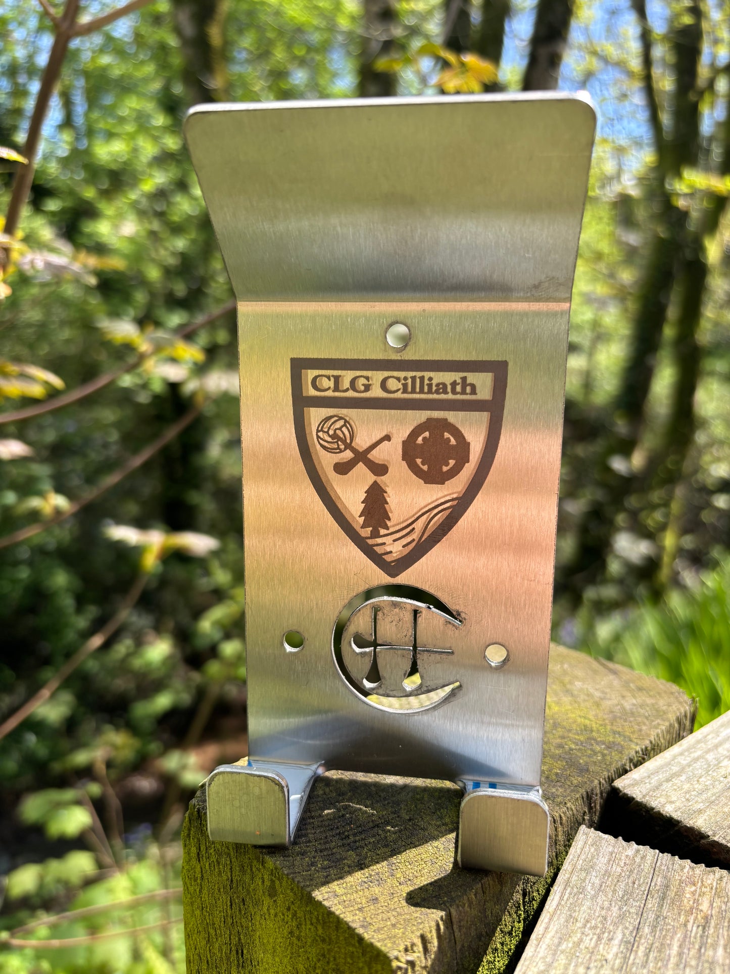 A stainless steel Dual Star hurling holder with a logo cut into the design, featuring a helmet hook and a hurley hook, placed against a grey background.