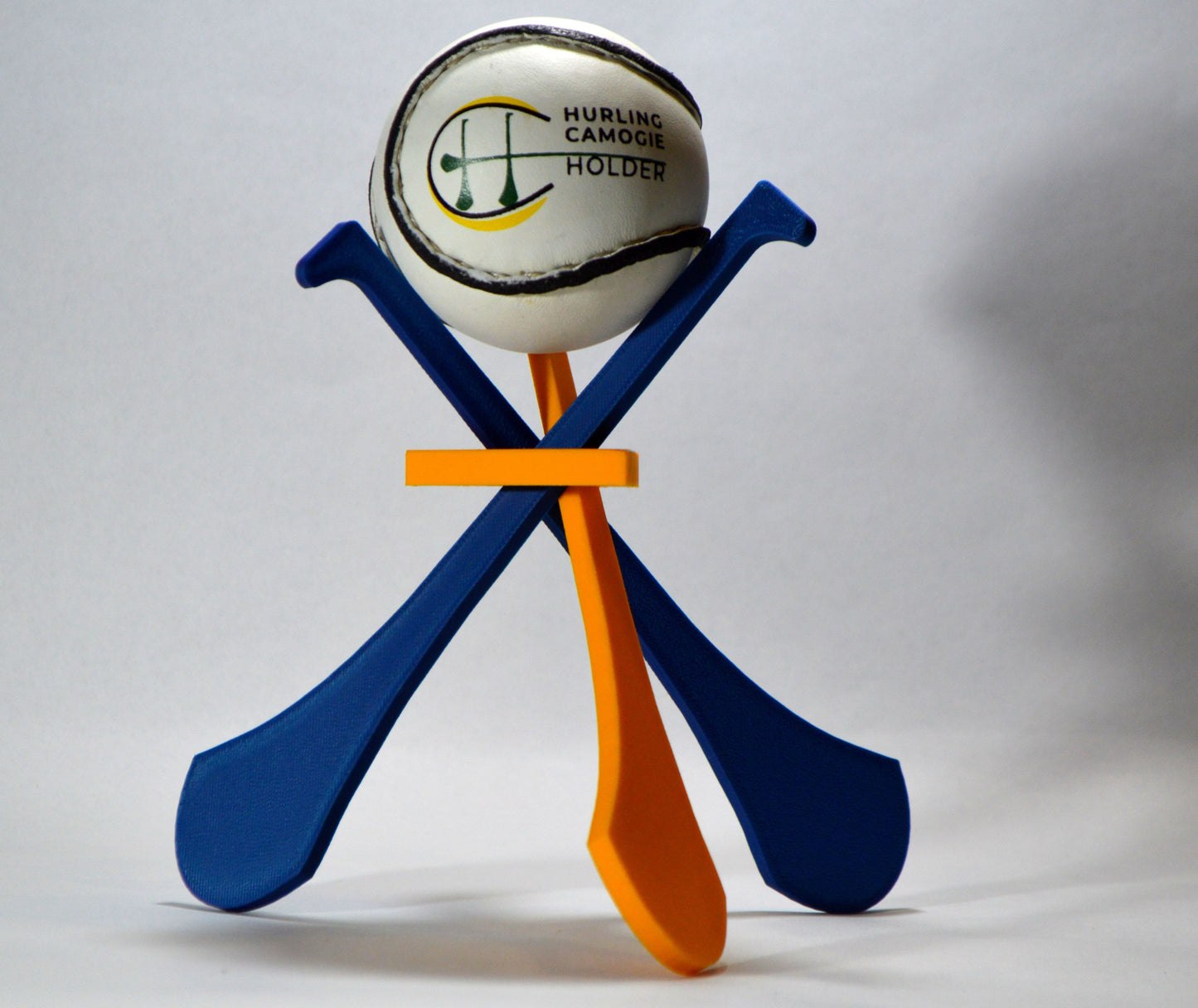 A display stand with a small hurley board and a sliotar ball, featuring blue and yellow colors.