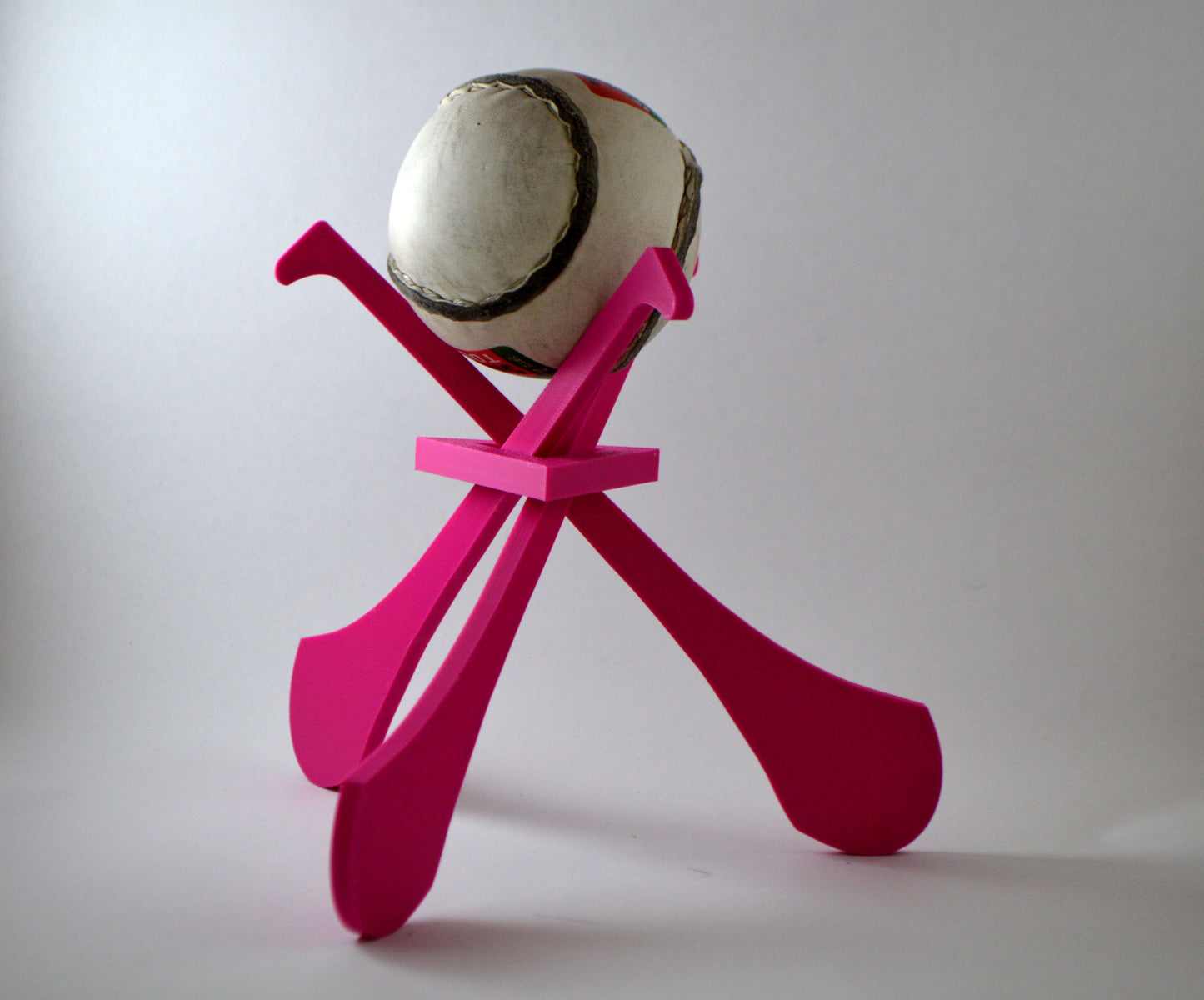 A display stand with a small hurley board and a sliotar ball, featuring pink colours.