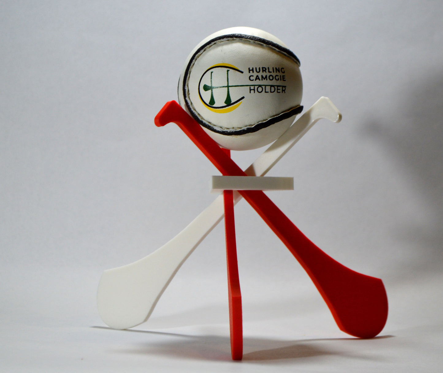 A display stand with a small hurley board and a sliotar ball, featuring blue and yellow colors.
