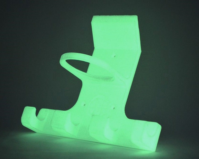 A UV light hurling camogie holder in translucent green plastic stand or holder with a curved ring-like loop and a flat base, shown against a dark grey background.