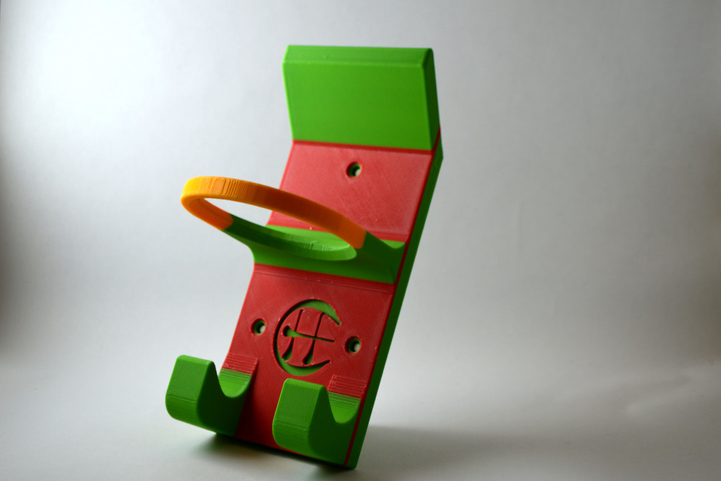 A red and green and yellow hurling holder with a logo cut into the design, featuring a helmet hook and a hurley hook and a sliotar holder.