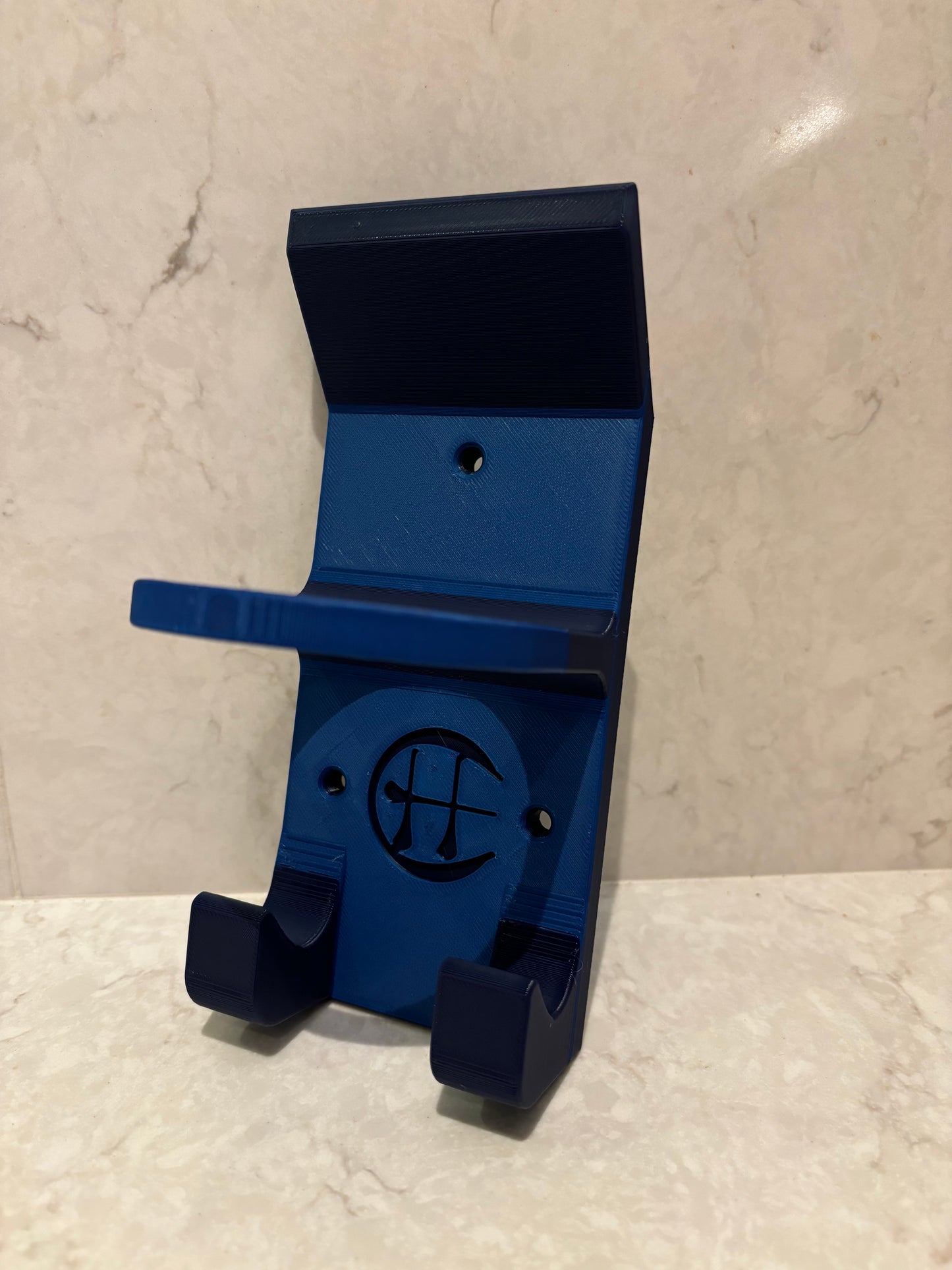 A blue and navy hurling holder with a logo cut into the design, featuring a helmet hook and a hurley hook and a sliotar holder.
