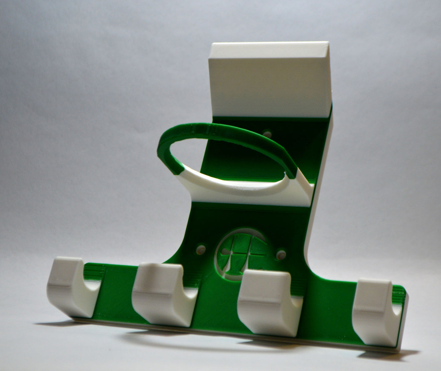 A green and white triple trinity hurley holder designed to hold equipment for the sport of hurling, featuring hooks for a helmet, sliotar, and multiple hurleys