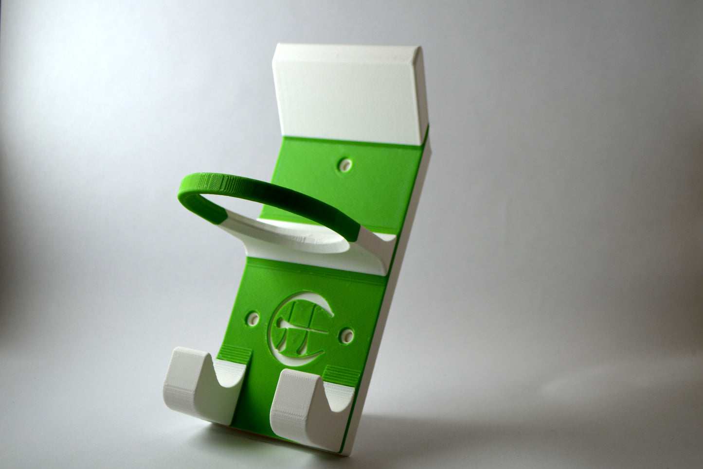 A white and green hurling holder with a logo cut into the design, featuring a helmet hook and a hurley hook and a sliotar holder.