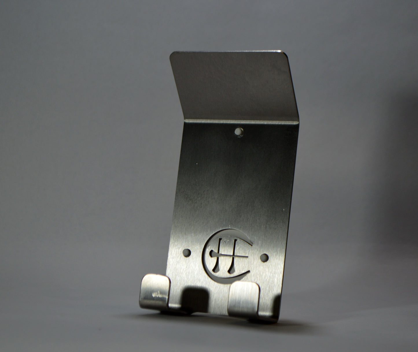 A stainless steel Dual Star hurling holder with a logo cut into the design, featuring a helmet hook and a hurley hook, placed against a grey background.