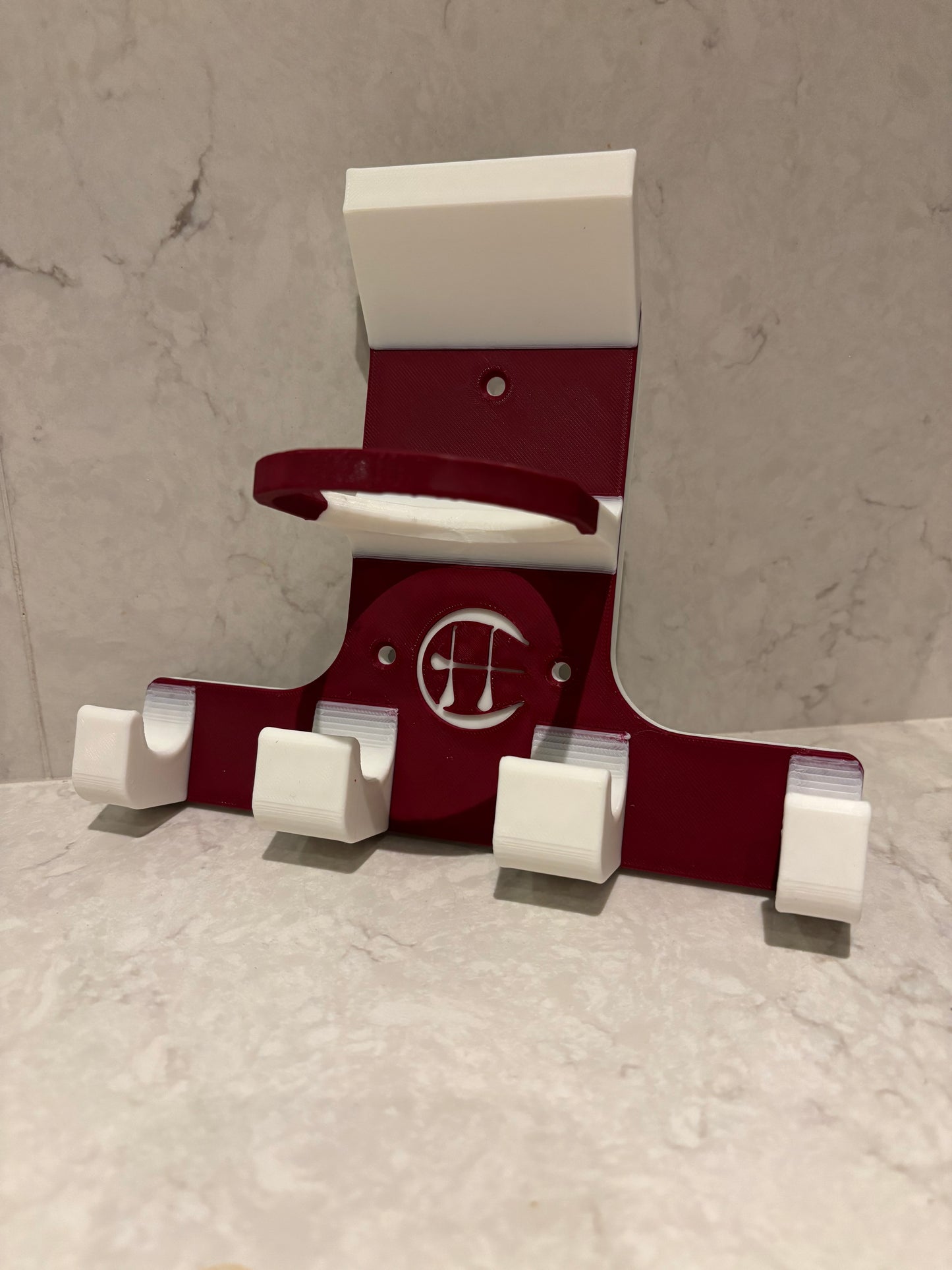 A maroon and white triple trinity hurley holder designed to hold equipment for the sport of hurling, featuring hooks for a helmet, sliotar, and multiple hurleys.