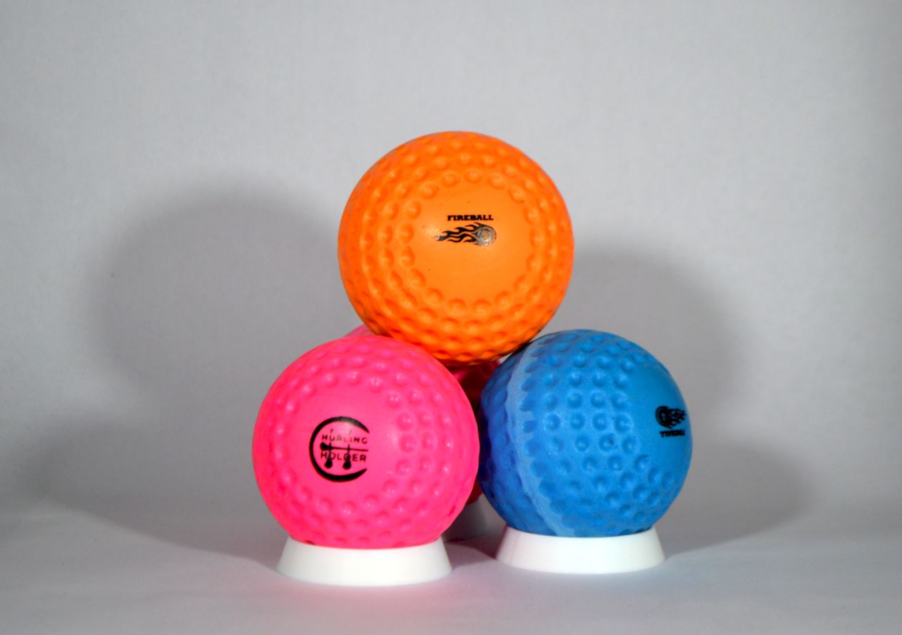 Three textured fireballs / speedballs in orange, pink, and blue, each resting on a small white circular base against a light grey background.