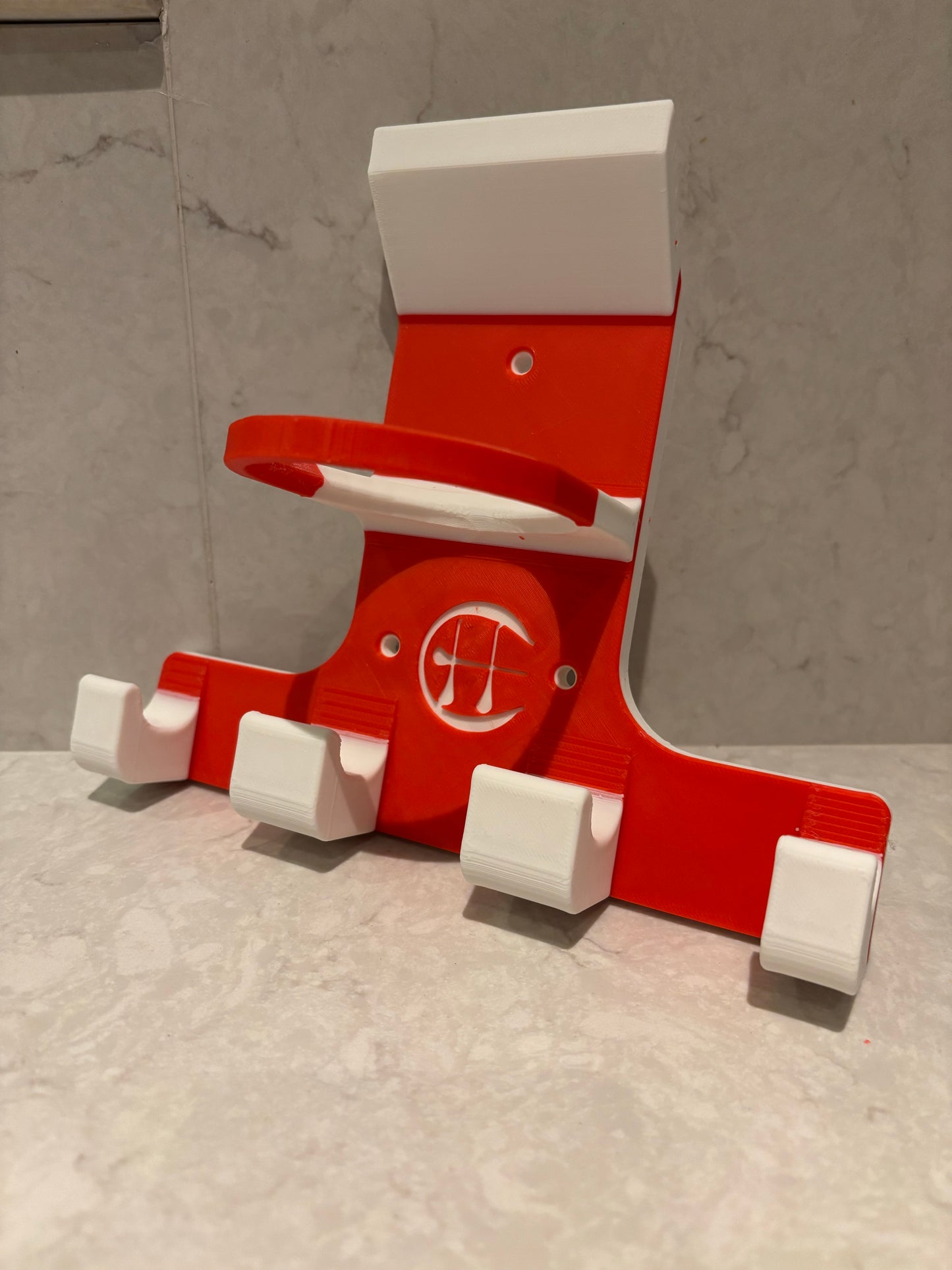 A red and white triple trinity hurley holder designed to hold equipment for the sport of hurling, featuring hooks for a helmet, sliotar, and multiple hurleys.