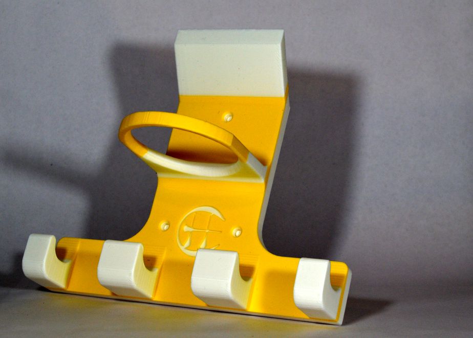 A yellow and white plastic hurling camogie holder photographed against a plain grey background.